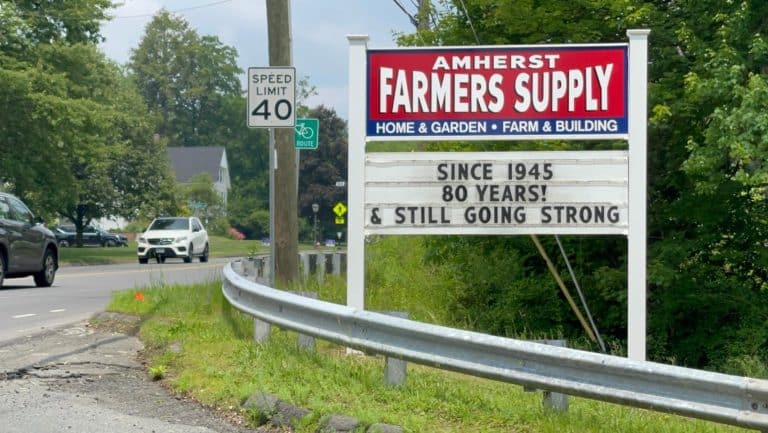 A roadside marquee letter sign announces that Amherst Farmers Supply is turning 80.