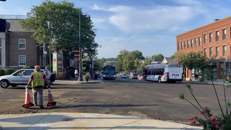 A construction worker moves traffic cones as work at the Main Street, Amity Street, North Pleasant Street, and South Pleasant Street intersection continues